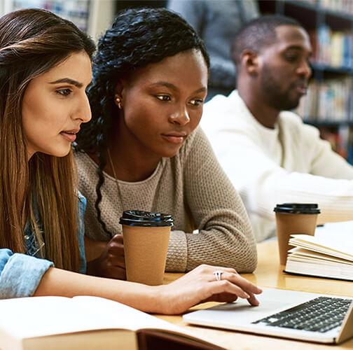 two students studying at a laptop in the library